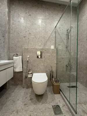 a bathroom with a toilet and a glass shower at Karak Plaza Residences in Kerak
