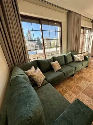 a green couch in a living room with a large window at 5/ Antica jabalal-lwebdeh in Amman
