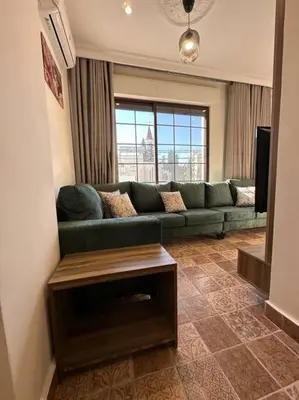 a living room with a green couch and a television at 5/ Antica jabalal-lwebdeh in Amman