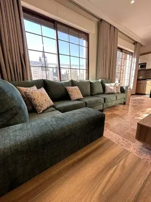 a living room with a green couch in a room with windows at 5/ Antica jabalal-lwebdeh in Amman