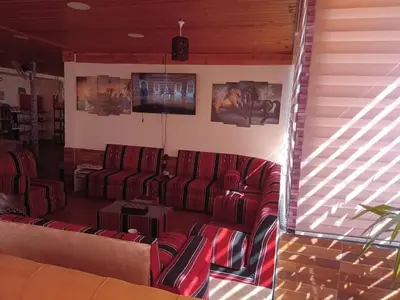 a waiting room with red chairs and a flat screen tv at Petra inbox Hostel in Wadi Musa