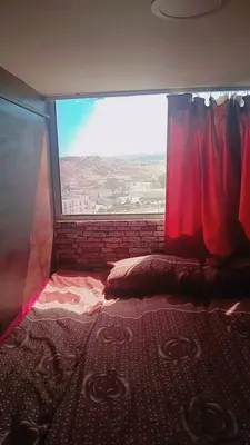 a bed in a room with a large window at Petra inbox Hostel in Wadi Musa