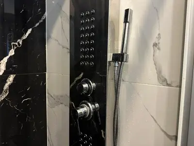 a shower door with a hose in a bathroom at Luxury Abdoun apartment in Amman