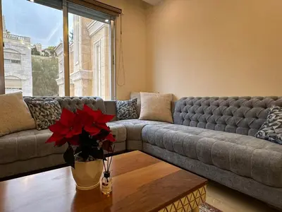a living room with a couch and a vase with red flowers at Luxury Abdoun apartment in Amman