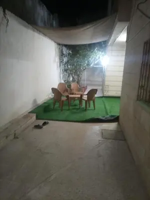 a room with a table and chairs on a green floor at Decapolis with garden in Irbid