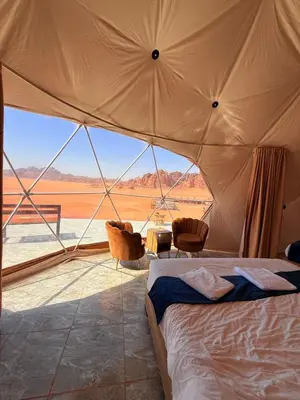 a bedroom with a bed in a tent with a view at Luxury tent camp in Wadi Rum