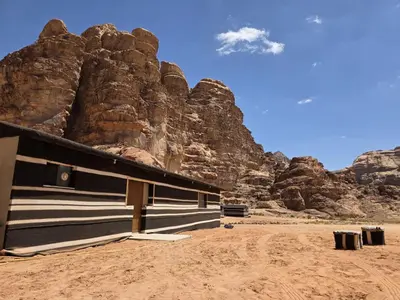 a building in front of a rocky mountain at Luxury tent camp in Wadi Rum