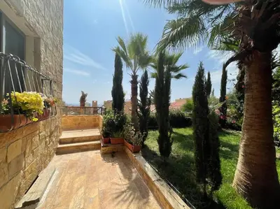 a balcony with palm trees and a house at Horizon Villa in Amman