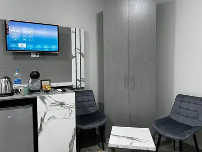 a kitchen with two chairs and a tv on the wall at Downtown Inn Madaba in Madaba