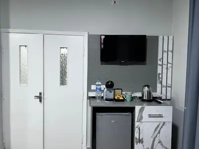 a kitchen with white cabinets and a tv on the wall at Downtown Inn Madaba in Madaba