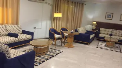 a living room with couches and a table and chairs at Conord Hotel in Amman