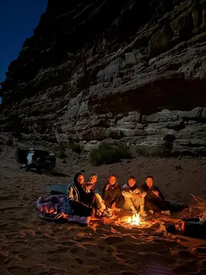 a group of people sitting around a bonfire on the beach at Lucas Camp Wadi Rum in Wadi Rum