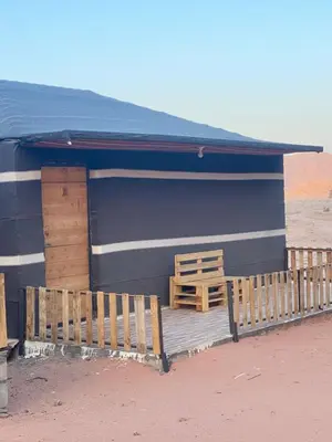 a blue building with a porch and a wooden fence at Lucas Camp Wadi Rum in Wadi Rum