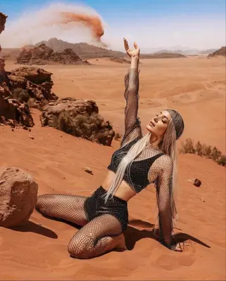 a woman in a black dress sitting in the desert at RUM MOON lUXURY CAMP in Wadi Rum