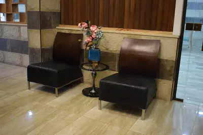 two chairs and a table and a vase with flowers at Nour Hotel in Amman