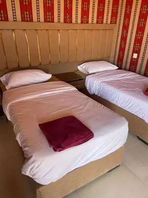 two beds with white sheets and a red blanket at Dessert flowers wadi rum in Disah