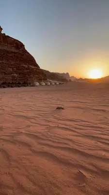 a desert with the sun setting in the horizon at Dessert flowers wadi rum in Disah