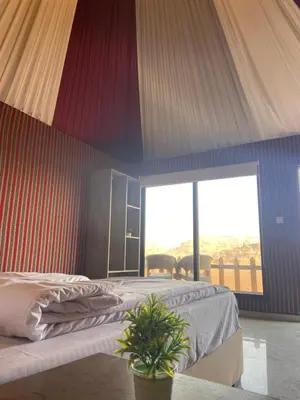 a bedroom with a bed and a large window at Dessert flowers wadi rum in Disah