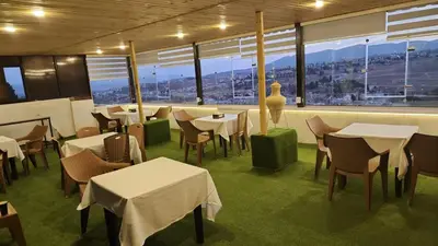 a restaurant with white tables and chairs and windows at Dream Hotel jerash in Jerash
