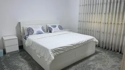a bedroom with a white bed with blue and white pillows at Luxury Family Apartment With Balcony in Amman