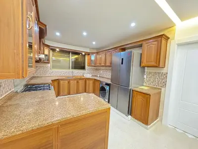 a kitchen with wooden cabinets and a stainless steel refrigerator at Luxury Family Apartment With Balcony in Amman