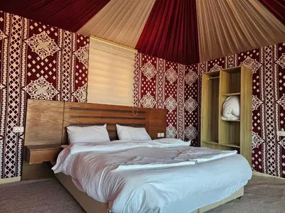 a bedroom with a large bed with red and white wallpaper at WADI RuM GRAND in Wadi Rum