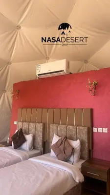 two beds in a tent with a sign on the wall at Nasa desert luxury camp in Wadi Rum