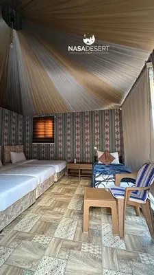 a bedroom with a bed and two chairs in a tent at Nasa desert luxury camp in Wadi Rum