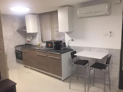 a kitchen with a counter and a table with stools at ‘C’ DAZZLING MODERN 2 BDRM APT IN KHALDA Free WIFI in Amman