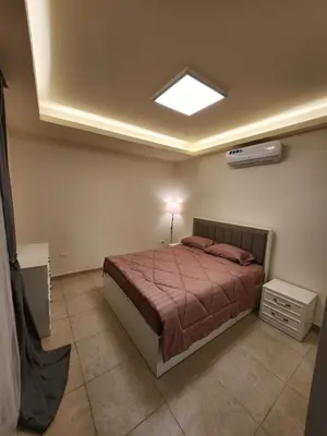 a bedroom with a large bed and a light at Dair Ghbar - Amman Apartment in Amman