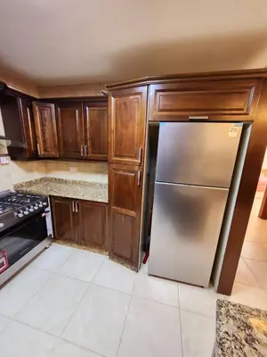 a kitchen with wooden cabinets and a stainless steel refrigerator at Dair Ghbar - Amman Apartment in Amman