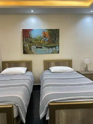 two beds in a room with a painting on the wall at Classy Guesthouse in Madaba
