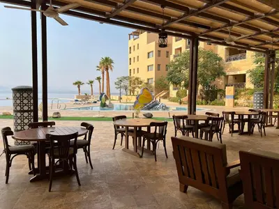 a patio with tables and chairs and a view of the ocean at EP1 TWO BEDROOM APARTMENT AT Samarah Resort in Sowayma