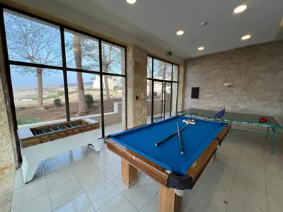 a pool table in a room with windows at EP1 TWO BEDROOM APARTMENT AT Samarah Resort in Sowayma