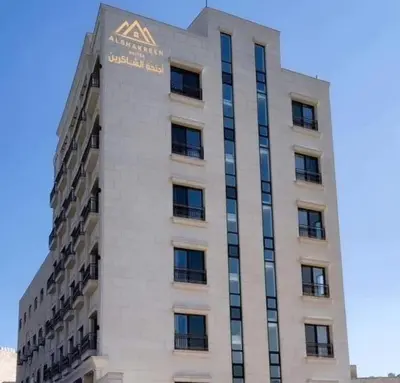 a tall white building with a sign on it at Alshakreen suites in Amman