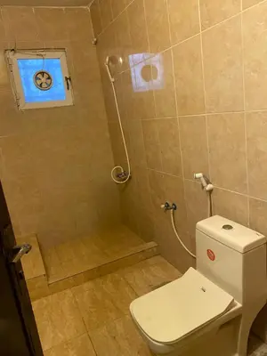 a bathroom with a toilet and a shower with a window at Magical Rosemary Chalet in Al Mashāriqah