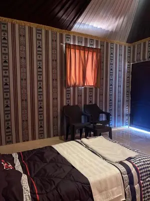 a bedroom with a bed and a window and a chair at nature camp in Wadi Rum