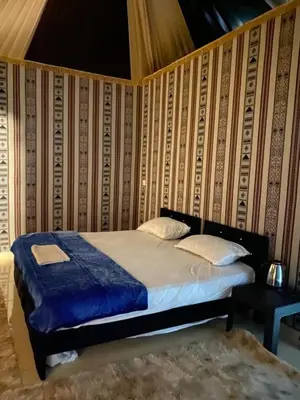 a bedroom with a bed in a room with a wall at nature camp in Wadi Rum