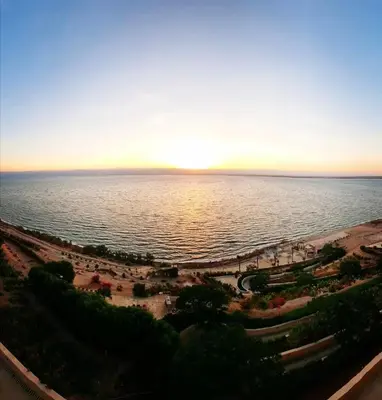 a view of a beach with the sun setting over the water at E21 Samarah Resort Apartments in Sowayma