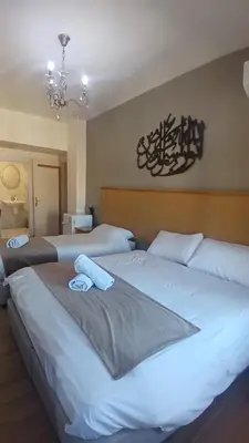 two beds in a bedroom with a chandelier at Moab Land Hotel in Madaba