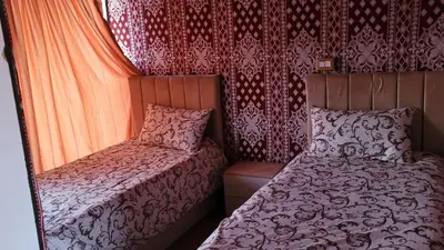 a small bedroom with two beds and red curtains at Rum Gonesh Luxury Camp in Wadi Rum