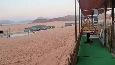a building on the side of a beach with a table at Rum Gonesh Luxury Camp in Wadi Rum