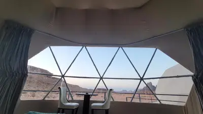 a large window in a room with a table and chairs at Rum Gonesh Luxury Camp in Wadi Rum