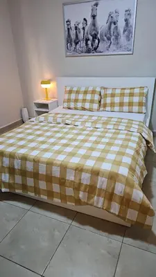 a bed with a yellow and white plaid blanket on it at 2 bedrooms apartment no 18 in Amman