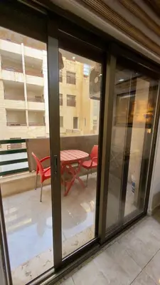 a sliding glass door with a table and chairs on a balcony at 2 bedrooms apartment no 18 in Amman