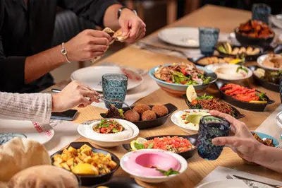 a group of people sitting around a table eating food at The Abdali Boulevard Hotel in Amman