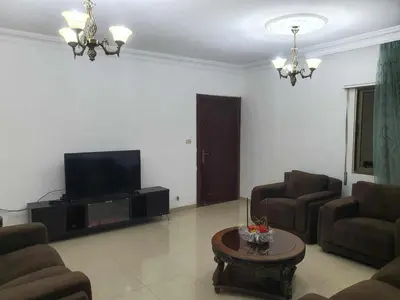 a living room with a tv and two chairs and a table at Noor Apartment in Amman