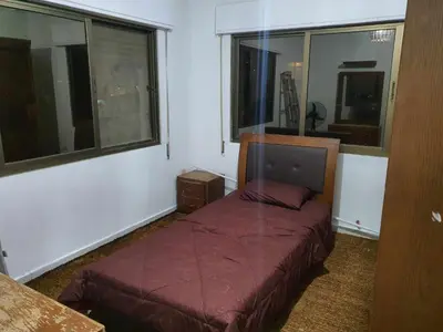 a bedroom with a bed in a room with windows at Noor Apartment in Amman