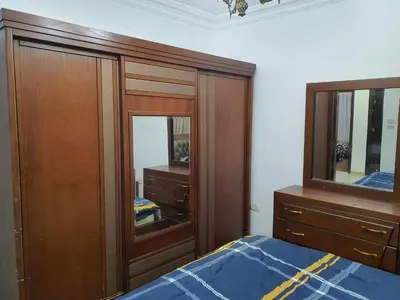 a bedroom with a bed and a dresser and a mirror at Noor Apartment in Amman
