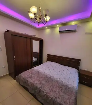 a bedroom with a bed and a ceiling with purple lights at MOTAMEZ APARTMENTS in Amman